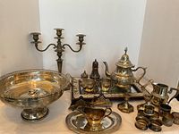 Full lot displayed together showing all items including large pedestal bowl, candelabra, tea pot and cream jug, mirrored tray, napkin rings, and shakers.