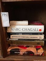 Books stacked in a shelf showing titles including Marc Chagall, E.B. Cox sculpture, Bettmann Portable Archive, Picasso, and a Museum art book by Abrams.