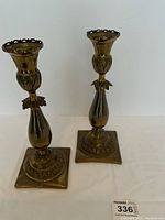 Pair of brass candlesticks upright on white background