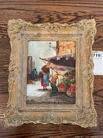 Full view of framed oil painting showing woman shopping at market with detailed carved frame