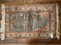 Full front view of silk Persian prayer rug laid flat on hardwood floor