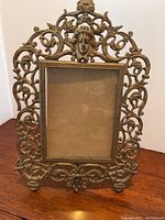 Front view of Victorian brass ornate picture frame showing central female face motif and decorative scrollwork