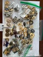 Assorted clip-on and screw-back earrings in multiple clear zip-top bags on white surface