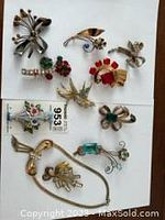 Nine brooches arranged on white background showing variety of shapes and colors