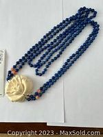 Coiled full-length view showing deep blue beads and central carved rose pendant
