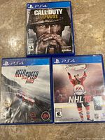 Photo showing all three PS4 game cases: Call of Duty WWII, NHL 16, and Need for Speed Rivals.