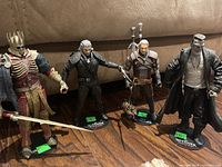 Four Witcher action figures on individual stands placed on wooden surface