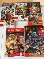 Boxed LEGO sets and book arranged showing front artwork. Includes Lava Dragon, Wild Wool, two Heroica sets, and LEGO Ninjago book.