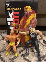 Lot showing Hollywood Hulk Hogan book and two WWE wrestling figures in front of the book cover.