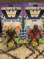 Two sealed WWE Masters Of The Universe style action figures of The Fiend Bray Wyatt and Kane with price stickers on packaging showing $40 and $20 respectively.