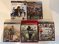 Photo showing five PS3 game cases: Game Demo Disc, Medieval Moves, two Call of Duty Modern Warfare games, and Grand Theft Auto V.