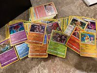 Pokémon cards spread out showing various holo and reverse holo cards including Orbeetle, Tyrantrum, and Maractus