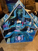 Front view of the Frozen themed doll house showing upper and lower rooms with furniture and staircases