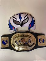 Top-down view of the Rey Mysterio style wrestling mask and WWE Intercontinental Championship belt showing main details and condition.