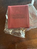 Closed maroon card holder with Yugioh Trading Card Game embossed logo on front.