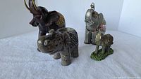 Set of four ceramic elephant figurines displayed together showing differences in size and decoration