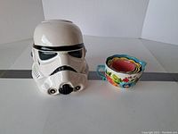 Front view of Star Wars Stormtrooper cookie jar next to Pioneer Woman floral nested measuring cups.