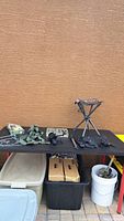 Lot overview on black table showing portable folding seat, fishing reel with repair kit, utility tool, and suspenders