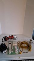 Lot displaying Skil angle grinder, flashlight, power outlet extension strip and yellow work light with extension cord.