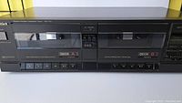 Front angle view of the black Technics RS-T19 double cassette deck showing two cassette compartments labeled Deck A and Deck B with control buttons underneath.