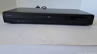 Front view of Toshiba SD-1800U DVD player showing disc tray, control buttons, and display.