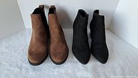 Front view of brown and black women's ankle boots side by side on white surface.