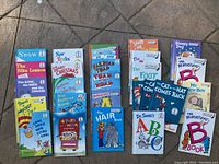 Top-down photo of 26 children's books laid out on concrete, showing colorful covers of Dr. Seuss and related titles.