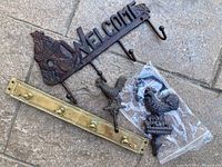 Iron 'Welcome' wall hook with rooster design and four hooks, brass hook rack with five hooks, two brass rooster figurines, one still in plastic.