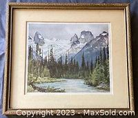 Framed vintage print featuring a mountain landscape with pine trees, a river, and cloudy sky. Signed bottom left by Frederick H. Brigden.