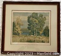 Framed print with nature scene of trees and water with autumn colors, signature visible at bottom left corner.
