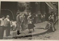 Close-up of the black and white photo showing the street scene with a girl being admired and several men looking on, featuring a scooter on the street.
