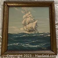 Framed oil painting showing a multi-masted sailing ship at sea, with ocean waves and sky background. Signature visible on lower right corner.