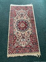 Full view of rectangular area rug with central medallion in red, cream, and navy colors on dark green carpet