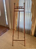 Full view of the wooden easel showing its height and width, standing near a window with natural light.