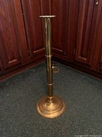 Full view of the tall brass candlestick showing round base and straight shaft.