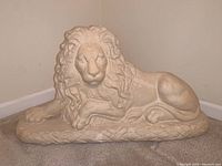 Full view of the large reclining lion sculpture showing shape, size, and base details.