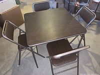 Full set of one square folding table with four matching folding chairs around it.