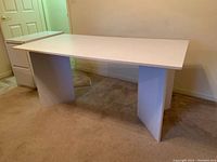 Full view of white sewing table desk showing flat rectangular top and V-shaped panel base.