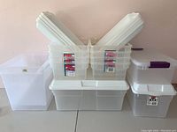 Wide view of assorted plastic storage bins stacked and grouped together showing size and lid types.