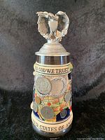Full view of stein decorated with US coins and eagle lid.