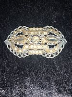 Front view of vintage filigree brooch pin showing detailed metalwork and central pearl bead