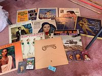 Collection of vintage LP vinyl albums and cassette tapes spread on the floor showing full album covers and cassette tapes.