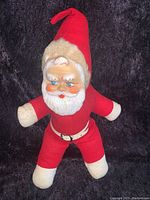 Full view of the stuffed Santa doll showing the outfit, hat, and rubber face
