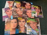 Photo showing twelve Vogue Pattern magazines from the late 1970s to mid 1980s, featuring female cover models and vintage fashion themes.