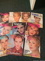 Photo showing 10 vintage Vogue Patterns magazines laid out, displaying front covers featuring women models and various fashion headlines from late 70s to mid-80s.