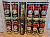 Twelve cans of tennis balls in total; ten cans are Penn brand Championship Extra-Duty Felt design and two are Wilson US Open design.