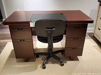 Desk with lockable drawers and black recessed writing pad on top with rolling chair placed behind it