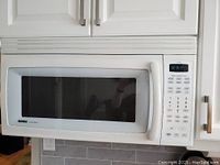 Front view of white Kenmore over-the-range microwave with visible keypad and glass door.