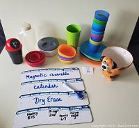Overview photo of lot showing all items including cups, bowls, containers, plates, dog planter, and dry erase calendar