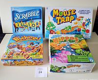 Top view of the four Milton Bradley board game boxes: Scrabble Junior, Mouse Trap, Buckaroo, and Hungry Hungry Hippos arranged on a flat surface.